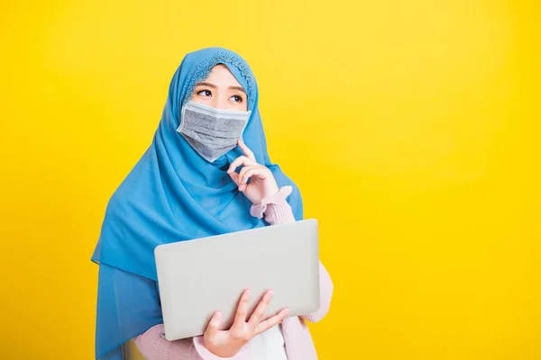 アジア系イスラム教徒アラブ人 幸せな美しい若い女性の肖像イスラム教の宗教的な摩耗ベールヒジャーブと顔のマスク彼女は病気のコロナウイルスを隔離保護するラップトップコンピュータを保持し 疑問を考えて — ストック写真