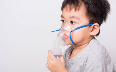 Kapalı Asyalı yüz, küçük çocuk hasta buhar spreyi nebulizer maskesi kullanıyor beyaz arka planda kendini soluyor, sağlık hizmetleri...