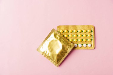 Dünya seks sağlığı ya da AIDS günü, prezervatif paketi ve doğum kontrol hapları hormonal doğum kontrol hapları, pembe arka planda izole edilmiş stüdyo çekimi, güvenli seks ve üreme sağlığı konsepti.