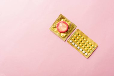 Dünya seks sağlığı ya da AIDS günü, prezervatif paketi ve doğum kontrol hapları hormonal doğum kontrol hapları, pembe arka planda izole edilmiş stüdyo çekimi, güvenli seks ve üreme sağlığı konsepti.