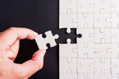Top view düz konum son parça beyaz kağıt yapboz oyunu çözülmesi için yerleştirilen son parçalar tam bir görev, stüdyo çekimi siyah arka plan, quiz hesaplama konsepti