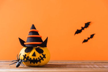 Komik Cadılar Bayramı dekorasyon partisi, şirin balkabağı hayaleti korkunç Jack o fener yüzü, siyah örümcek ve yarasalar ahşap masada, stüdyo çekimi turuncu arka planda, mutlu tatil konsepti