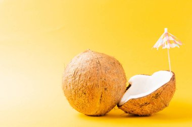 Mutlu hindistan cevizi günü konsepti, taze hindistan cevizi ve güneş şemsiyesi, stüdyo çekimi sarı arka planda izole edilmiş, plaj tropikal meyve yaz tatili