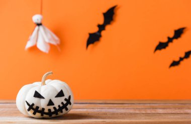 Komik Cadılar Bayramı dekorasyon partisi, şirin balkabağı hayaleti ürkütücü Jack o fener yüzü, siyah örümcek ve yarasalar ahşap masada, stüdyo çekimi turuncu arka planda, mutlu tatil konsepti