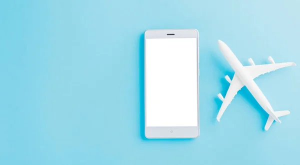 World Tourism Day, Top view flat lay of minimal toy model plane, airplane, and smartphone blank screen, studio shot isolated on a blue background, accessory flight holiday concept