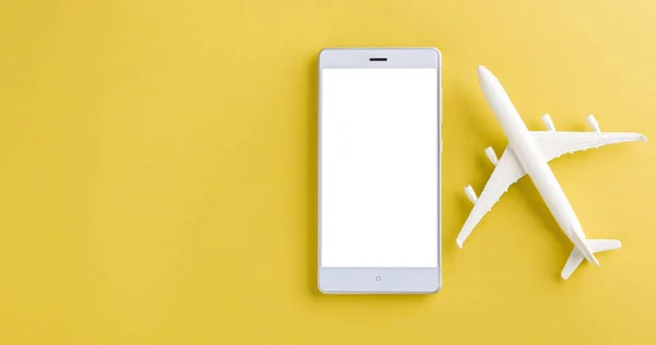 World Tourism Day, Top view flat lay of minimal toy model plane, airplane, and smartphone blank screen, studio shot isolated on a yellow background, accessory flight holiday concept