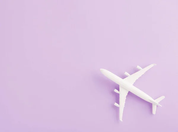 World Tourism Day, Top view flat lay of minimal toy model plane, airplane, studio shot isolated on a purple background, accessory flight holiday concept