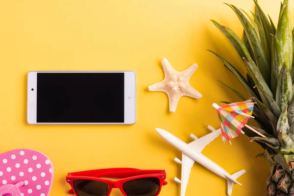 Celebrate Summer Pineapple Day Concept, Top view flat lay of funny pineapple, sunglasses, model plane, and smartphone blank screen, isolated on yellow background, Holiday summertime in tropical