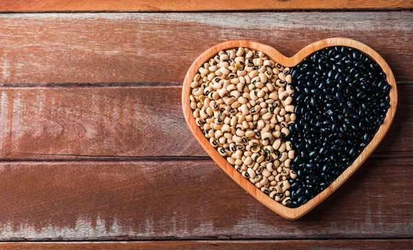World food day, black bean and soybean seeds or white cowpea beans on a heart plate and wooden background, studio shot