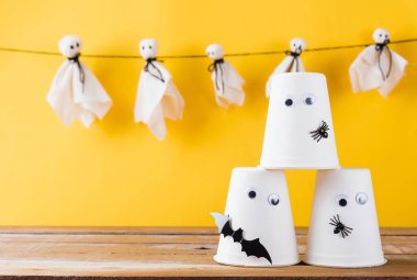 Komik Cadılar Bayramı süsleme partisi, Bebek beyaz hayaletler korkunç suratlar asma ve cadılar bayramı el sanatları kağıt bardak hayaleti, stüdyo resmi izole edilmiş, Mutlu bayramlar el işi konsepti