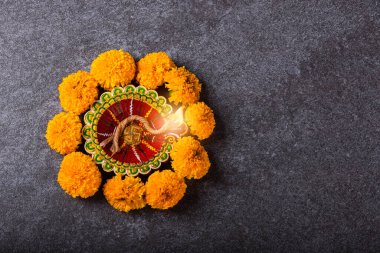 Üst tepedeki kil Diya 'yı ya da yağ lambasını ya da sarı çiçeği aydınlatıyor, stüdyo çekimleri somut arka planda, Hinduizm rangolisinin dekorasyonu, Mutlu Deepavali ya da Diwali festivali konsepti