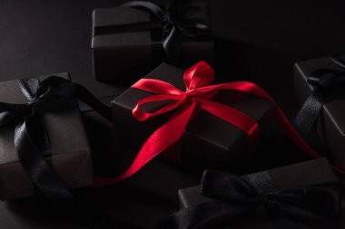 Kara Cuma alışverişi konsepti, hediye kutusunun üst görüntüsü siyah kağıt ve siyah kurdeleyle kaplanmış kutunun etrafında kırmızı kurdele, arka planda stüdyo çekimi.