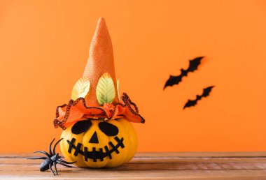 Komik Cadılar Bayramı dekorasyon partisi, şirin balkabağı hayaleti korkunç Jack o fener yüzü, siyah örümcek ve yarasalar ahşap masada, stüdyo çekimi turuncu arka planda, mutlu tatil konsepti
