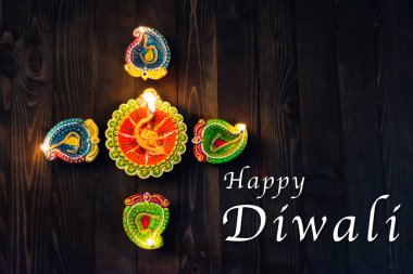 Üst tepedeki kil Diya ya da petrol lambası için ateş yakıyor, stüdyo siyah ahşap arka planda çekiliyor, Hinduizm Rangoli Dekorasyonu, Mutlu bayramlar Deepavali ya da Diwali festivali konsepti