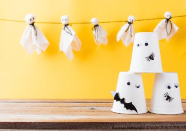 Komik Cadılar Bayramı süsleme partisi, Bebek beyaz hayaletler korkunç suratlar asma ve cadılar bayramı el sanatları kağıt bardak hayaleti, stüdyo resmi izole edilmiş, Mutlu bayramlar el işi konsepti