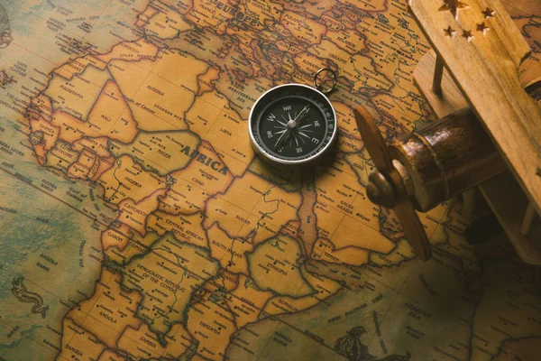 古いコンパス発見とヴィンテージ紙アンティーク世界地図の背景に木製の飛行機 レトロスタイルの地図旅行地理ナビゲーション — ストック写真