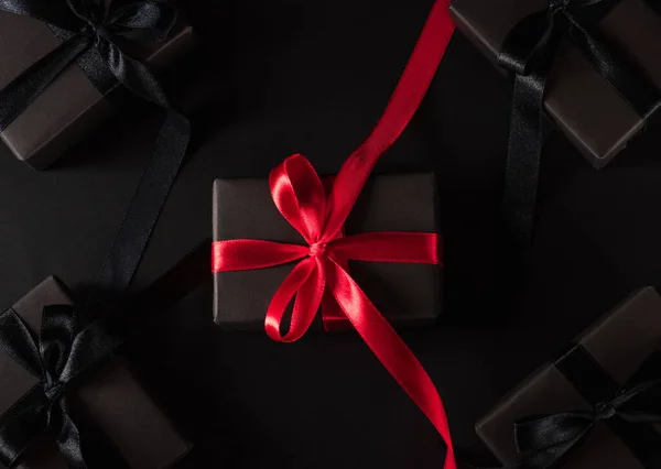 黑色星期五购物理念 礼品盒头像用黑纸和黑色蝴蝶带包裹着礼品盒 盒子周围用红色缎带 工作室用深色背景拍摄 — 图库照片