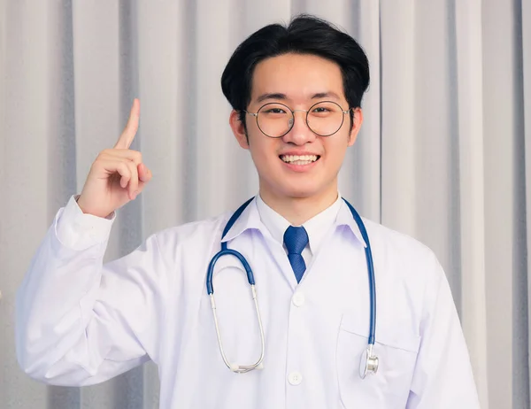 幸せなアジアの若いです医師ハンサムな男笑顔で制服と聴診器首ストラップ指を指す側に離れてとカメラを見て 医療医学の概念 — ストック写真