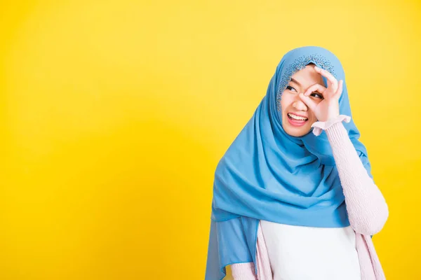 アジア系イスラム教徒アラブ人 幸せな美しい若い女性の肖像イスラム教の宗教的な摩耗ベールヒジャーブ面白い笑顔彼女は彼女の目の上に をサインを右ジェスチャーシンボルでジェスチャー指を表示孤立黄色の背景 — ストック写真