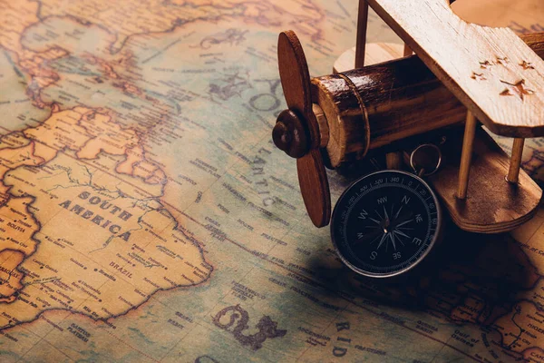 Old compass discovery and wooden plane on vintage paper antique world map background, Retro style cartography travel geography navigation