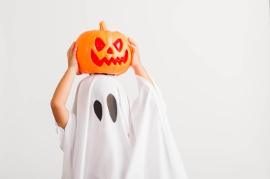 Komik Cadılar Bayramı Çocuğu kavramı, beyaz kostümlü küçük şirin çocuk Cadılar Bayramı hayaleti korkunç elinde turuncu kabak hayaleti, beyaz arka planda tek başına çekilmiş bir stüdyo resmi.
