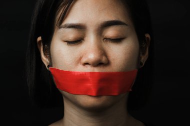 Asyalı bir kadın siyah arka planda kırmızı bantla gözlerini bağlıyor. Konuşma özgürlüğü sansürü ve konuşmayı durdurmak, Uluslararası İnsan Hakları Günü