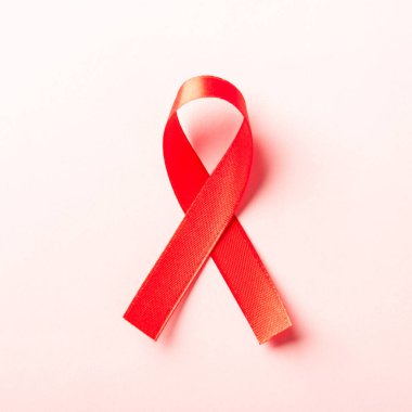 Kırmızı kurdele sembolü HIV, AIDS kanseri gölgeli farkındalık, pembe arka planda izole edilmiş stüdyo çekimi, sağlık sigortası konsepti, Dünya AIDS Günü