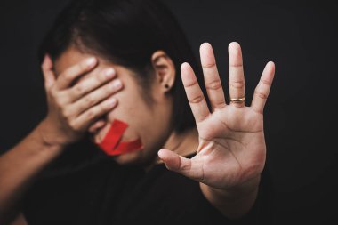 Ağzı kırmızı bantla saran ve el işaretini gösteren kadın siyah arka planda şiddet ve istismarı, insan ticaretini ve istismarı, Uluslararası İnsan Hakları Günü 'nü durdurdu.