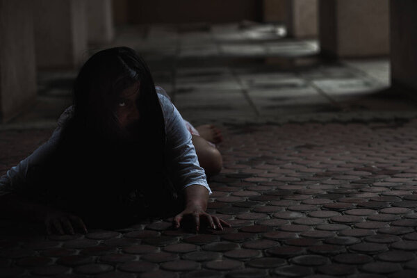 Женский зомби в крови. Призрак азиатки с кровью. Ужас страшный страх в темном доме жуткий ползающий шаг медленно выползает наружу. Хайр, закрывающая лицо своей камерой, концепция фестиваля Хэллоуин