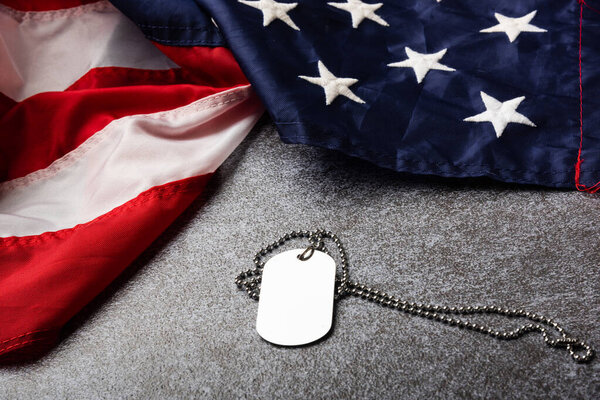 America United States flag and chain dog tags, military symbolizing, studio shot on concrete board background, US Veterans or Independence day concept