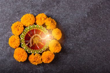Üst tepedeki kil Diya 'yı ya da yağ lambasını ya da sarı çiçeği aydınlatıyor, stüdyo çekimleri somut arka planda, Hinduizm rangolisinin dekorasyonu, Mutlu Deepavali ya da Diwali festivali konsepti