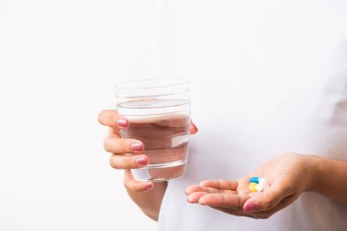 Yakın plan genç Asyalı kadın elinde haplarla hazır bir bardak suyla ilaç alıyor, beyaz arka plan, sağlık ve tıbbi eczane konseptine izole edilmiş stüdyo fotoğrafları çekiyor.