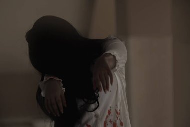 Kanlı dişi zombi. Kanlı Asyalı kadın hayalet. Evdeki korkunç korku. Karanlık ses tonu. Elini kaldır ve uzan. Yüzünü kaplayan yakın saç. Kameraya bakıyor. Cadılar Bayramı festivali konsepti.