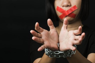 Asyalı bir kadın kırmızı yapıştırıcı bantla gözlerini bağlıyor ve elleri bağlı tercüman zinciri siyah arka planı var. Konuşma özgürlüğü sansürü ve konuşmayı durdurmak, Uluslararası İnsan Hakları Günü