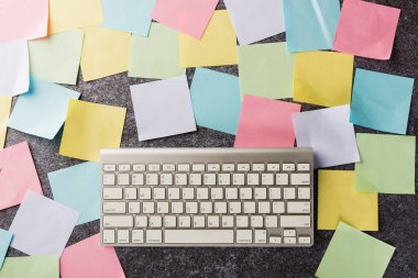 Beton zemin üzerinde modern bilgisayar klavyesi olan birçok boş kağıt yapıştırma not listesinin üzerinde, iş anımsatıcı bellek bugün konsepti