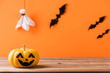 Komik Cadılar Bayramı dekorasyon partisi, şirin balkabağı hayaleti ürkütücü Jack o fener yüzü, siyah örümcek ve yarasalar ahşap masada, stüdyo çekimi turuncu arka planda, mutlu tatil konsepti