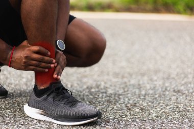 Kapatın Asyalı genç spor koşucusu. Siyah adam kol eklemli el takıyor. Ayak bileği burkulduğu için bacak ağrısı çekiyor.