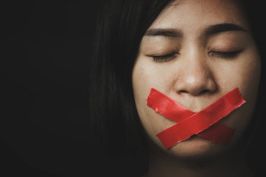 Asyalı bir kadın siyah arka planda kırmızı bantla gözlerini bağlıyor. Konuşma özgürlüğü sansürü ve konuşmayı durdurmak, Uluslararası İnsan Hakları Günü