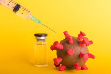 Kapalı plastisin hastalıkları hücreleri virüs aşısı ve koronavirüs salgını ve koronavirüs gribi şırıngası, sarı arka planda izole edilmiş stüdyo çekimi, salgın COVID-19 tıbbi sağlık
