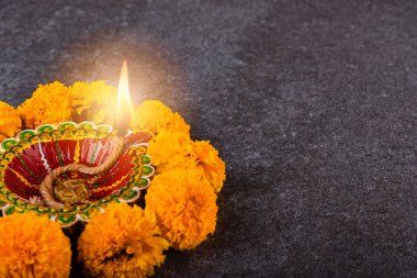 Üst tepedeki kil Diya 'yı ya da yağ lambasını ya da sarı çiçeği aydınlatıyor, stüdyo çekimleri somut arka planda, Hinduizm rangolisinin dekorasyonu, Mutlu Deepavali ya da Diwali festivali konsepti