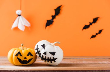 Komik Cadılar Bayramı dekorasyon partisi, şirin balkabağı hayaleti ürkütücü Jack o fener yüzü, siyah örümcek ve yarasalar ahşap masada, stüdyo çekimi turuncu arka planda, mutlu tatil konsepti