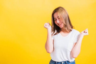 Asya Tayland mutlu portresi güzel şirin genç kadın tişörtü giyiyor kazanan ve şaşıran çığlığı atan ağzı açık, eller açık, stüdyo çekimleri izole edilmiş sarı arka plan ve fotokopi alanı