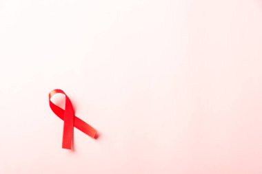 Kırmızı kurdele sembolü HIV, AIDS kanseri gölgeli farkındalık, pembe arka planda izole edilmiş stüdyo çekimi, sağlık sigortası konsepti, Dünya AIDS Günü