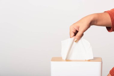 Genç kadın gribi. Beyaz mendiller için beyaz bir kutudan beyaz yüz dokusu alıyor. Stüdyo resmi beyaz arka planda izole edilmiş, sağlık sigortası konsepti.