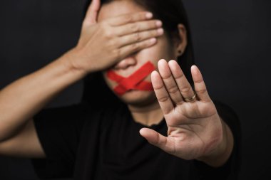 Ağzı kırmızı bantla saran ve el işaretini gösteren kadın siyah arka planda şiddet ve istismarı, insan ticaretini ve istismarı, Uluslararası İnsan Hakları Günü 'nü durdurdu.
