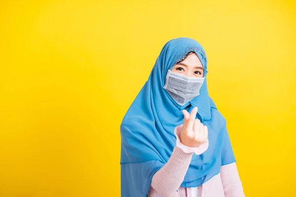 アジアのイスラム教徒アラブ幸せな美しい若い女性の肖像イスラム教の宗教的な摩耗ベールヒジャーブと顔のマスクは 隔離された黄色の背景の愛の指ミニハートシンボルを示しています — ストック写真