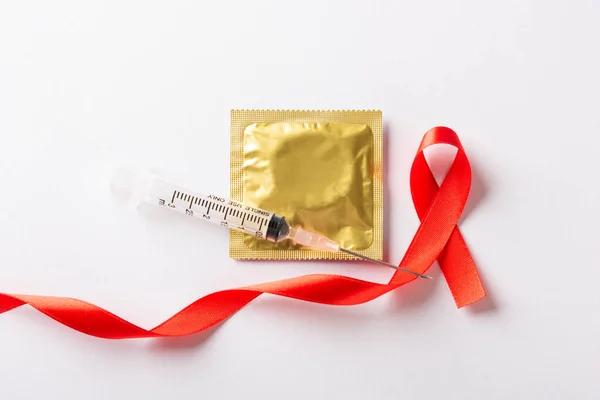 红弓带象征艾滋病毒 对艾滋病的认识 带阴影的避孕套和注射器 因白色背景而被隔离的演播室 医疗保健医学的性概念 世界艾滋病日 — 图库照片