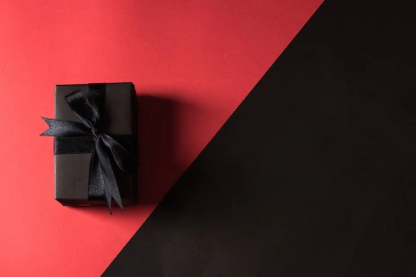 黑色星期五购物理念 顶部的礼品盒包装黑纸和黑色蝴蝶结带 工作室拍摄孤立在红色和黑色背景 — 图库照片