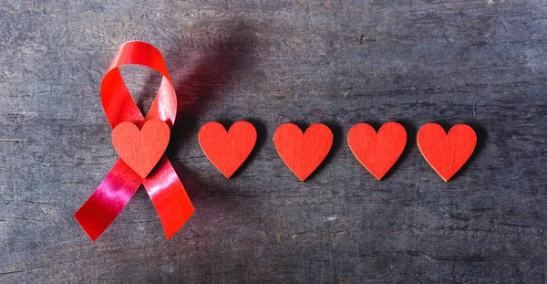 Red Ribbon Support HIV, AIDS and red Heart on wooden background and copy space for use