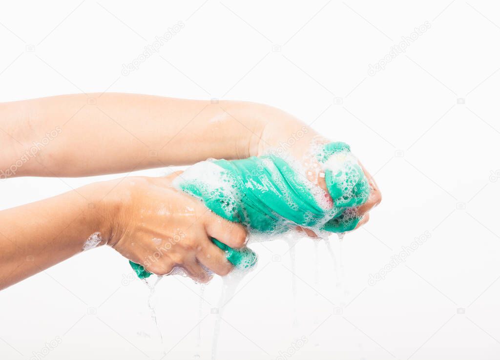 Closeup young Asian woman use hands wash color clothes. Female squeeze wring out wet fabric cloth with detergent have soapy bubble in water, studio shot isolated on white background, laundry concept
